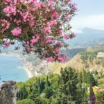 Beautiful postcard view with flowers over Taormina, Sicily