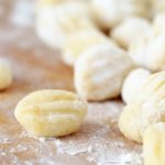 Homemade gnocchi on a flour-covered, wood surface