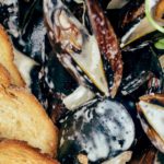 mussels in white cream sauce with bread and herbs