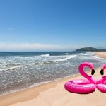 Inflatable pink flamingos on the desertted sand beach.
